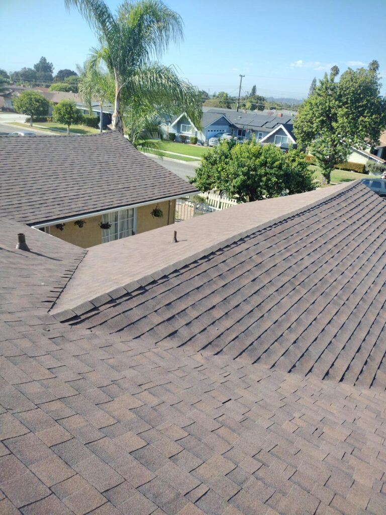New asphalt shingle roof installation on a residential home in Southern California with clean roof lines and nearby palm trees in a sunny neighborhood.